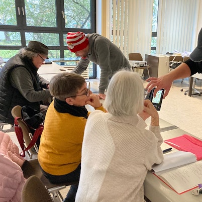 James Clark (r.) und Adam Ben Salem weisen im Seminar ältere Menschen im Umgang mit dem Smartphone ein.