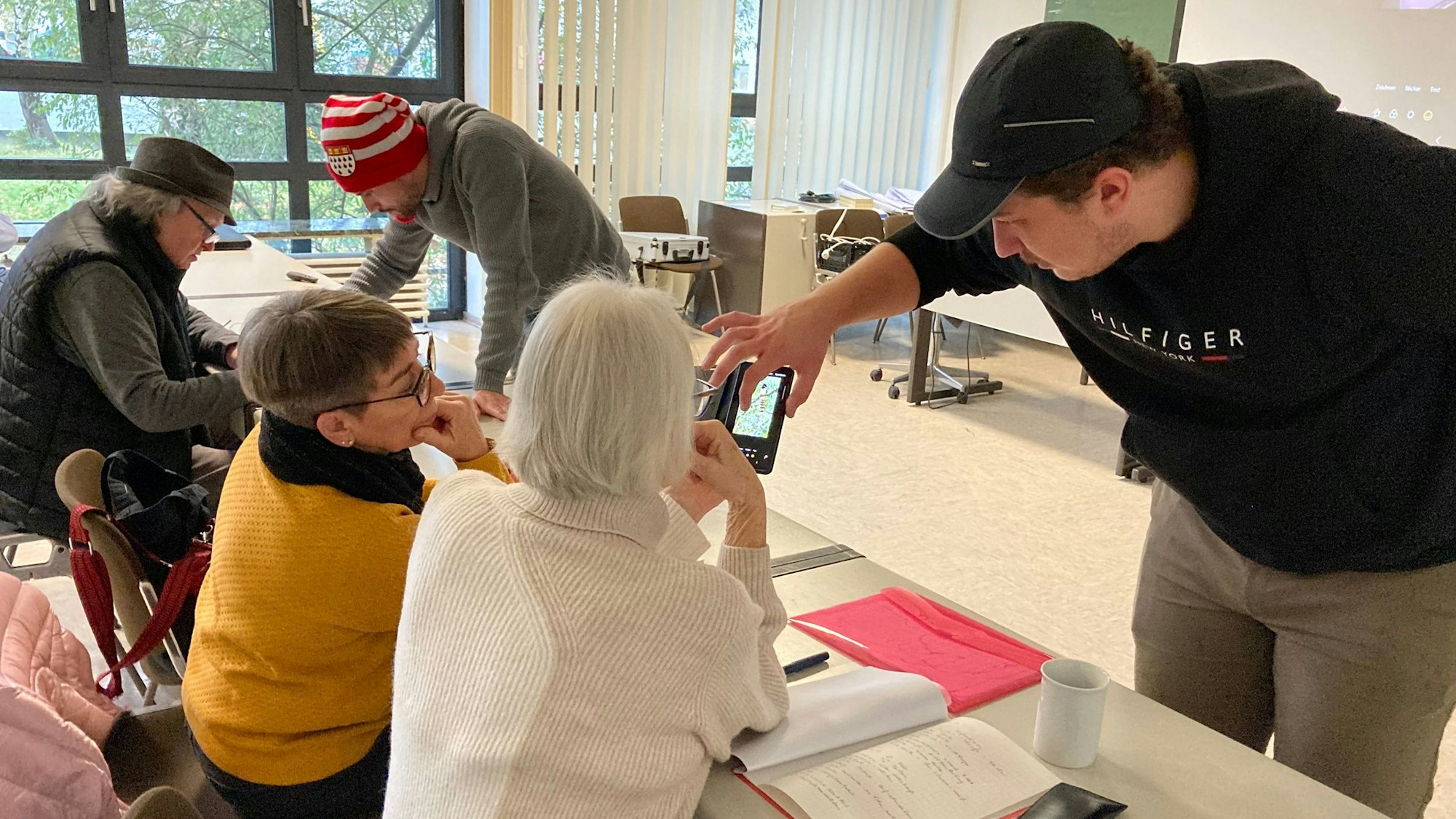 James Clark (r.) und Adam Ben Salem weisen im Seminar ältere Menschen im Umgang mit dem Smartphone ein.