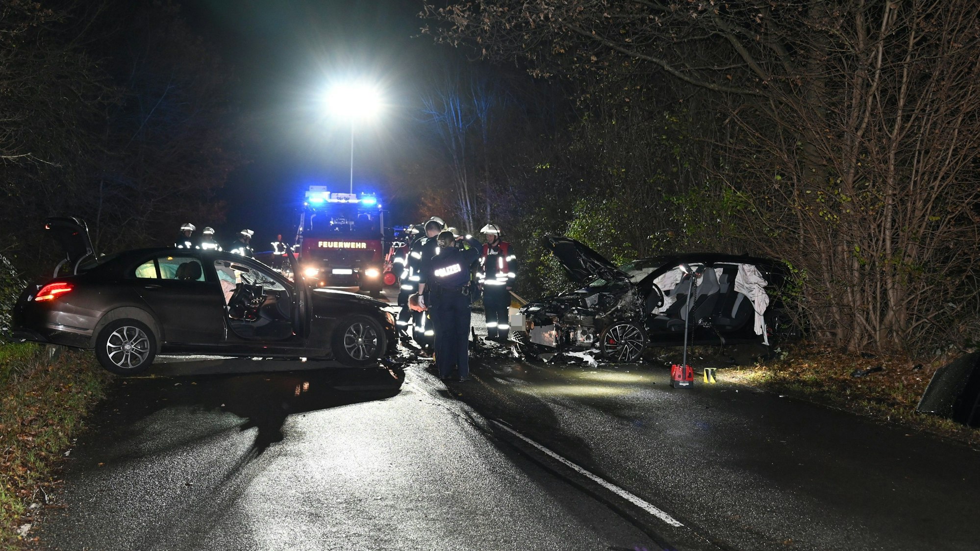 Zwei Autos stehen quer auf einer Straße. Rettungskräfte stehen neben den Wagen und untersuchen sie.