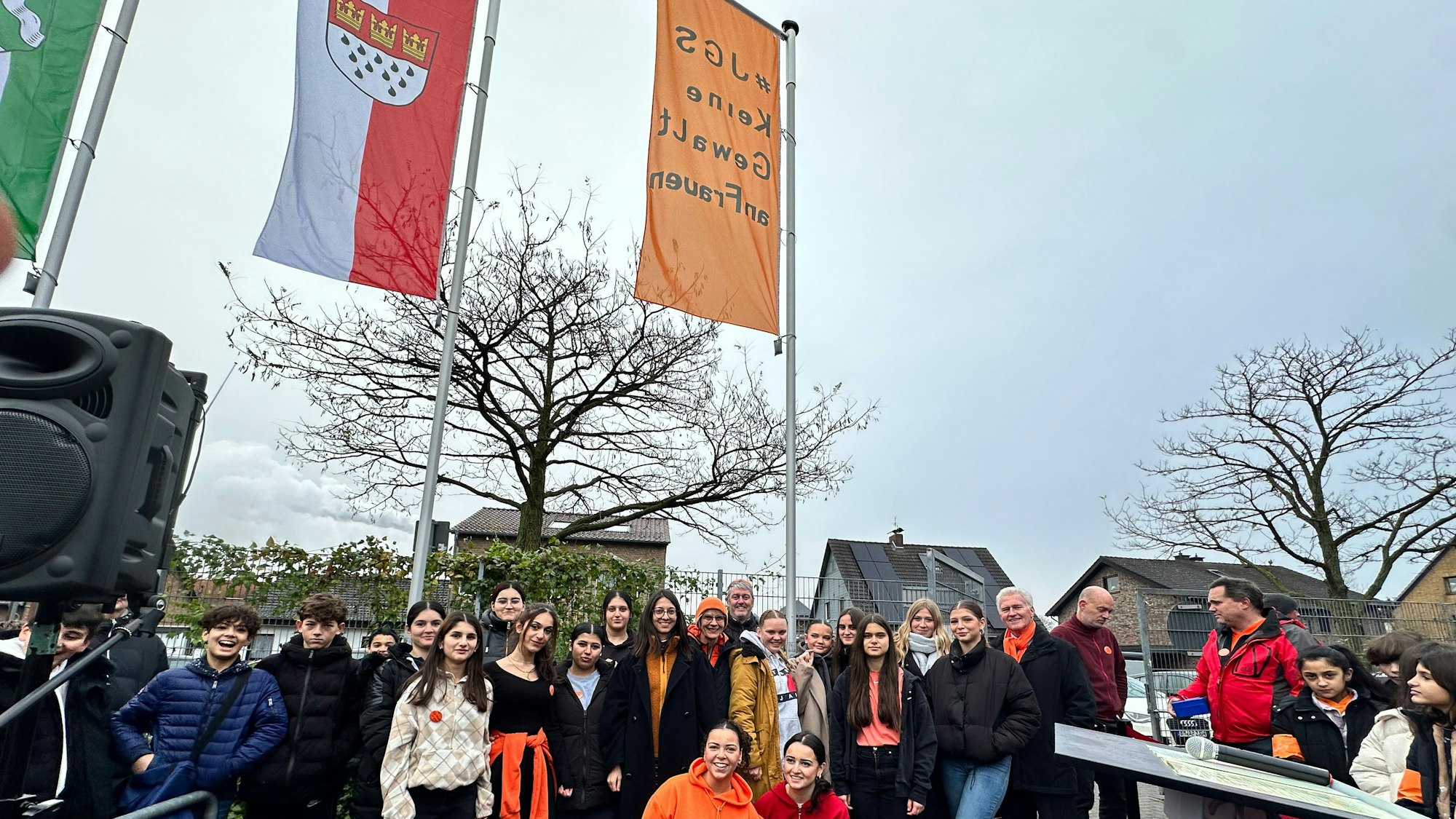 Gruppenfoto mit Schülern und Bezirksbürgermeister Manfred Giesen, die orangene Fahne und die mit dem Kölner Wappen im Hintergrund zu sehen.