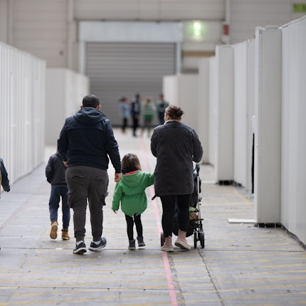 Eine Flüchtlingsfamilie geht durch die zu einer Massenunterkunft umfunktionierten Messehalle in Frankfurt.