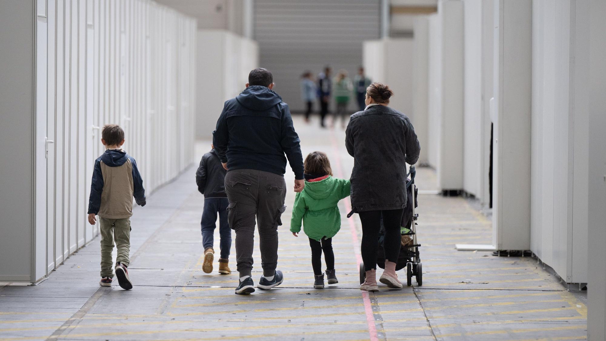 Eine Flüchtlingsfamilie geht durch die zu einer Massenunterkunft umfunktionierten Messehalle in Frankfurt.