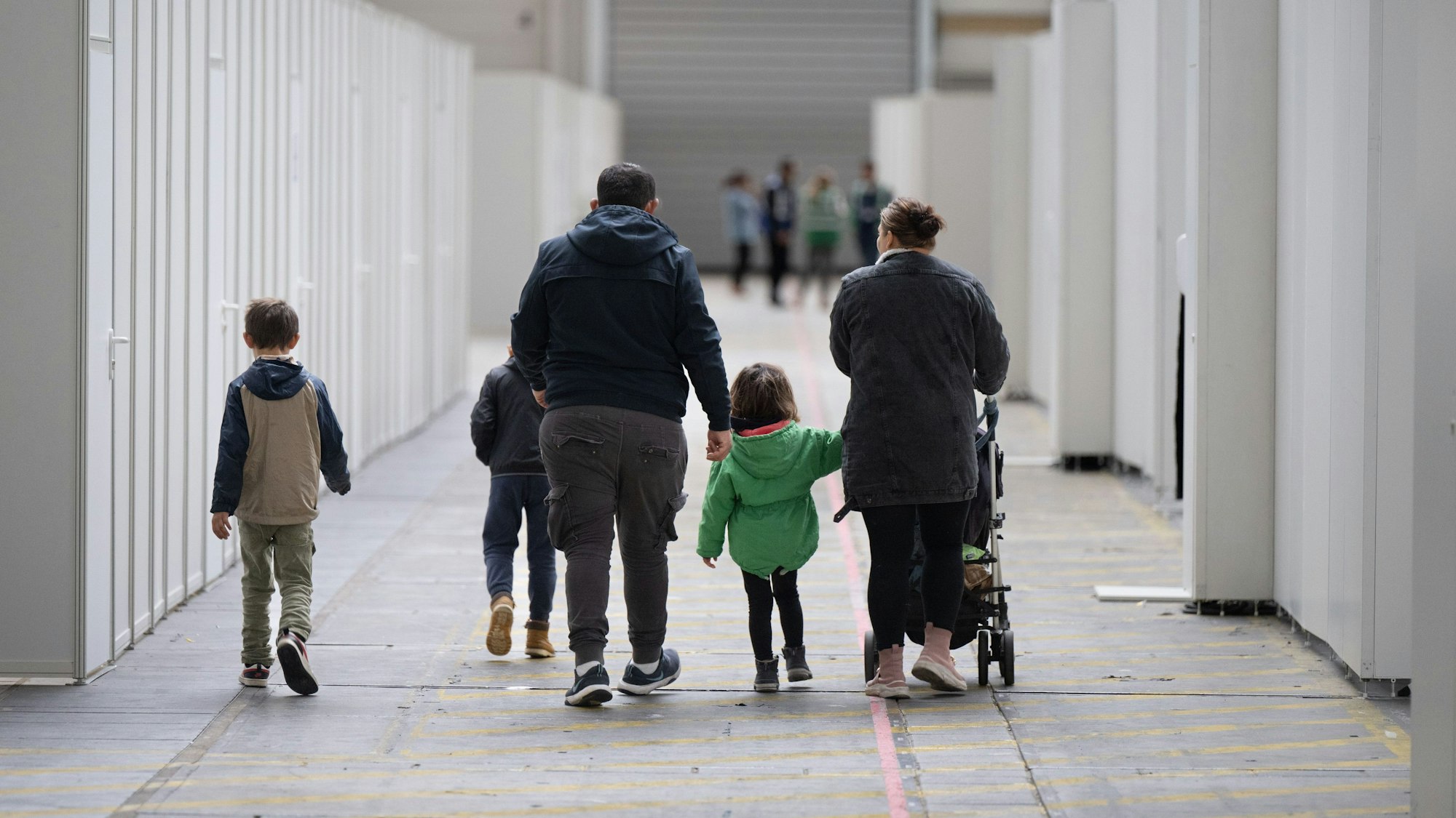 Eine Flüchtlingsfamilie geht durch die zu einer Massenunterkunft umfunktionierten Messehalle in Frankfurt.