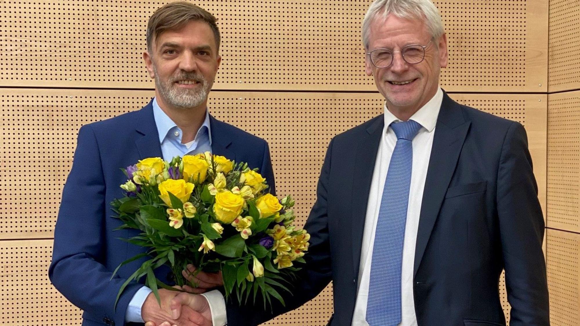 Das Bild zeigt Gerno Böll, frischgewählter Dezernent, wie er von Bürgermeister Dieter Freytag einen Blumenstrauß erhält.