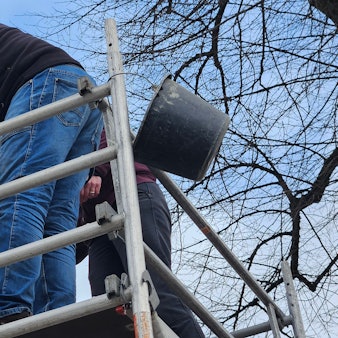 Ein Mann auf einem Gerüst arbeitet an einer steinernen Jesusfigur.