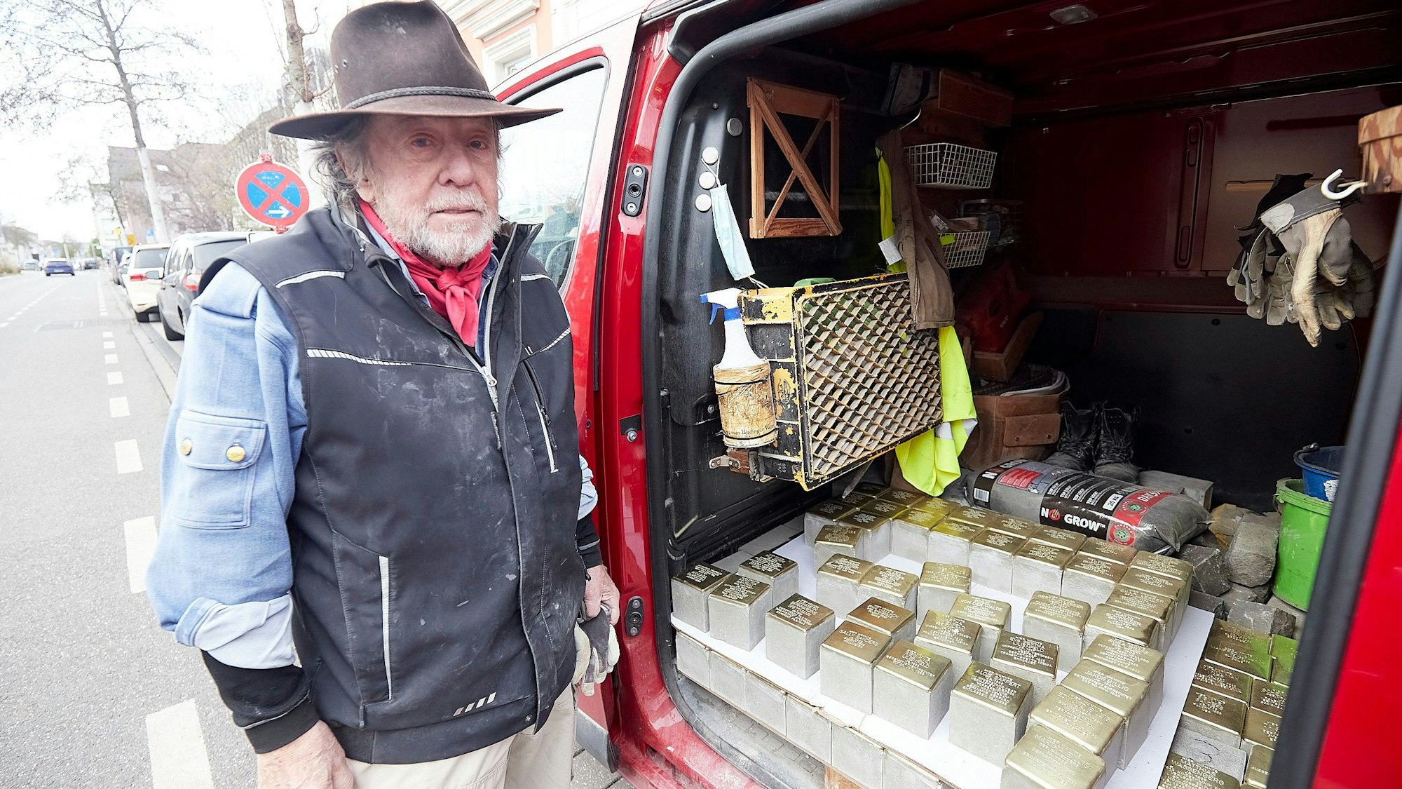 Der Künstler Gunter Demnig steht an seinem roten Kastenwagen und blickt auf die 40 Stolpersteine, die er in Euskirchen und Nettersheim verlegt.