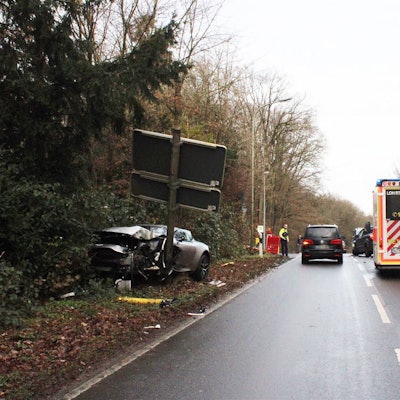Ein völlig demoliertes Auto steht an einem abgeknickten Schildertafelmast. Auf der Straße stehen Rettungsdienst- und Polizeifahrzeuge.