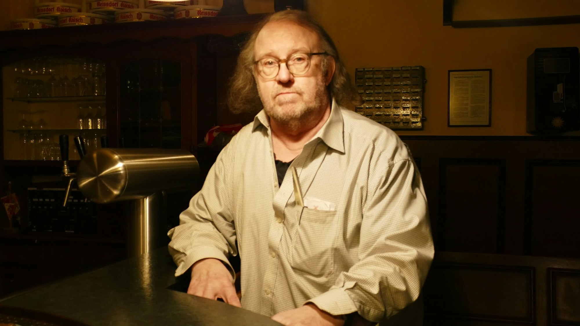 Ein älterer Herr mit wenig Haaren steht hinter einem Zapfhahn.
