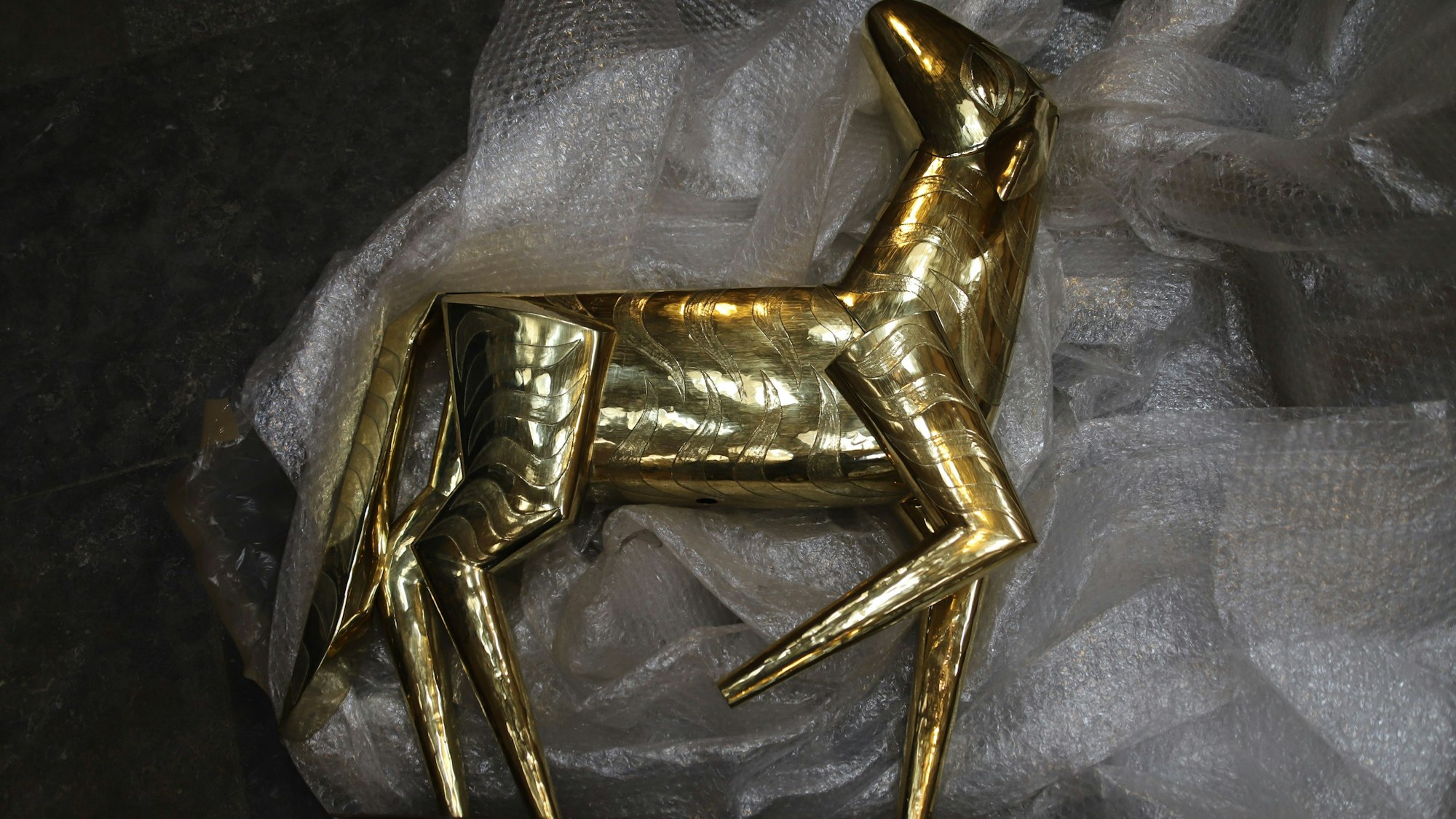 Das Lamm Gottes, ebenfalls aufpoliert, wird am Ende oberhalb der Aufhängung montiert und bildet mit Kreuz und Siegesfahne den oberen Abschluss des Kunstwerks.