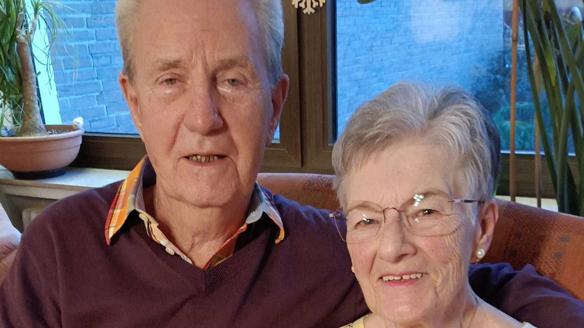 Ein Mann und eine Frau sitzen nebeneinander auf einem Sofa und lächeln.