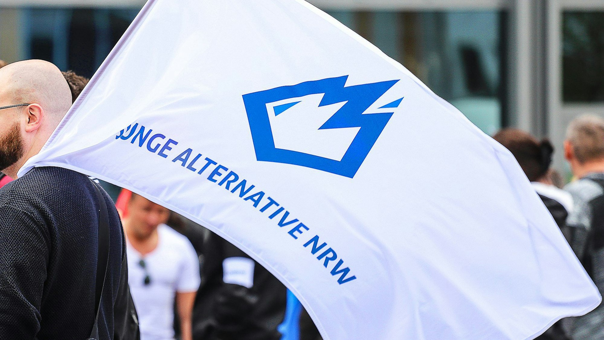 Ein Mitglied der „Jungen Alternative“ (JA), Jugendorganisation der AfD, trägt eine Fahne mit dem Logo der Organisation.