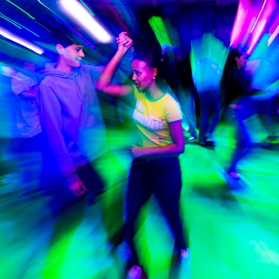 Charlise mit Tanzpartner Anton, eingetaucht in buntes Disco-Licht.