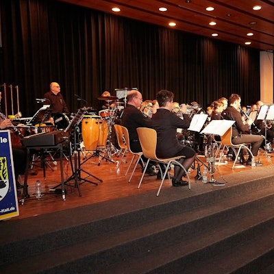 Die Aktiven der Musikkapelle Kall sitzen auf der Bühne der Aula in Steinfeld und geben ein Konzert.