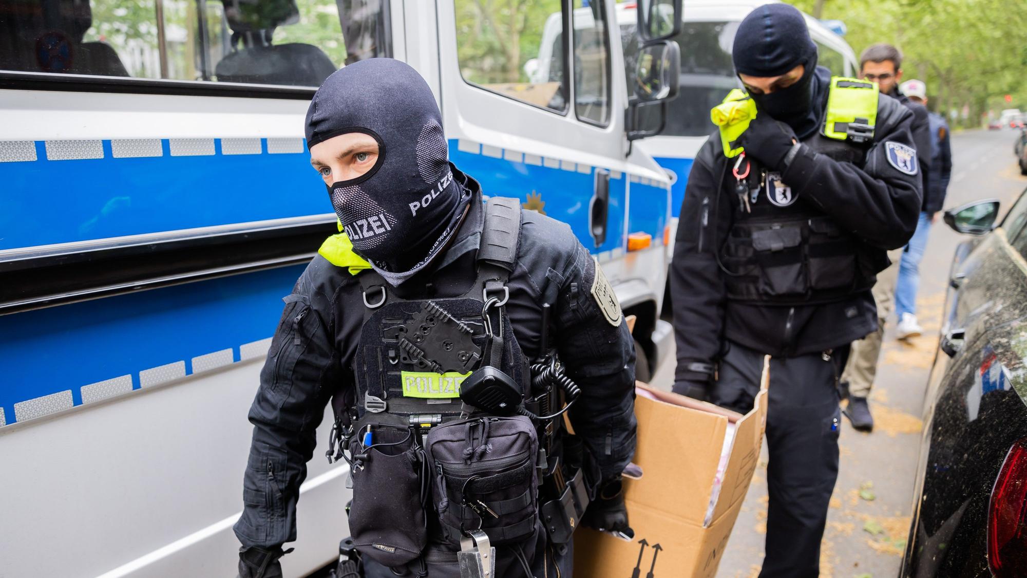 Polizisten tragen bei einer Hausdurchsuchung in Berlin-Kreuzberg einen Karton zu einem Fahrzeug.