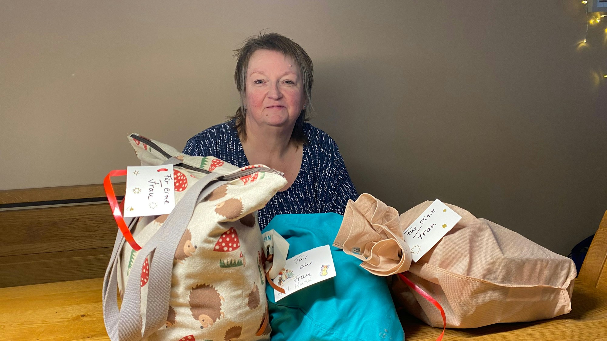 Pia Schüffelgen sitzt an einem Tisch, vor ihr liegen Weihnachtstüten für obdachlose Frauen.