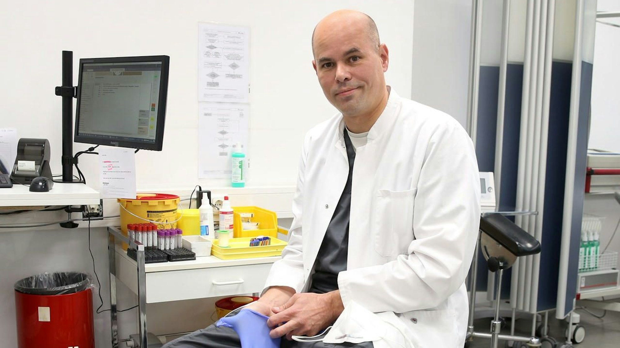 Tim Knoop sitzt auf einem Stuhl in einem Zimmer seiner Arztpraxis