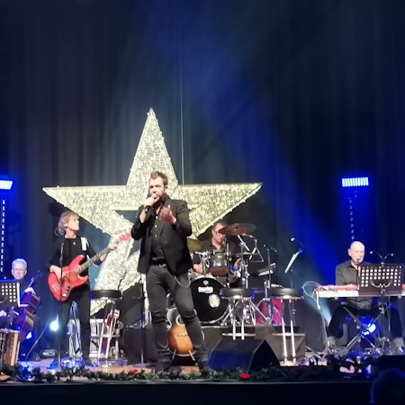 Die Band Paveier vor einem großen leuchtenden Stern auf der Bühne im Feierabendhaus Knapsack.