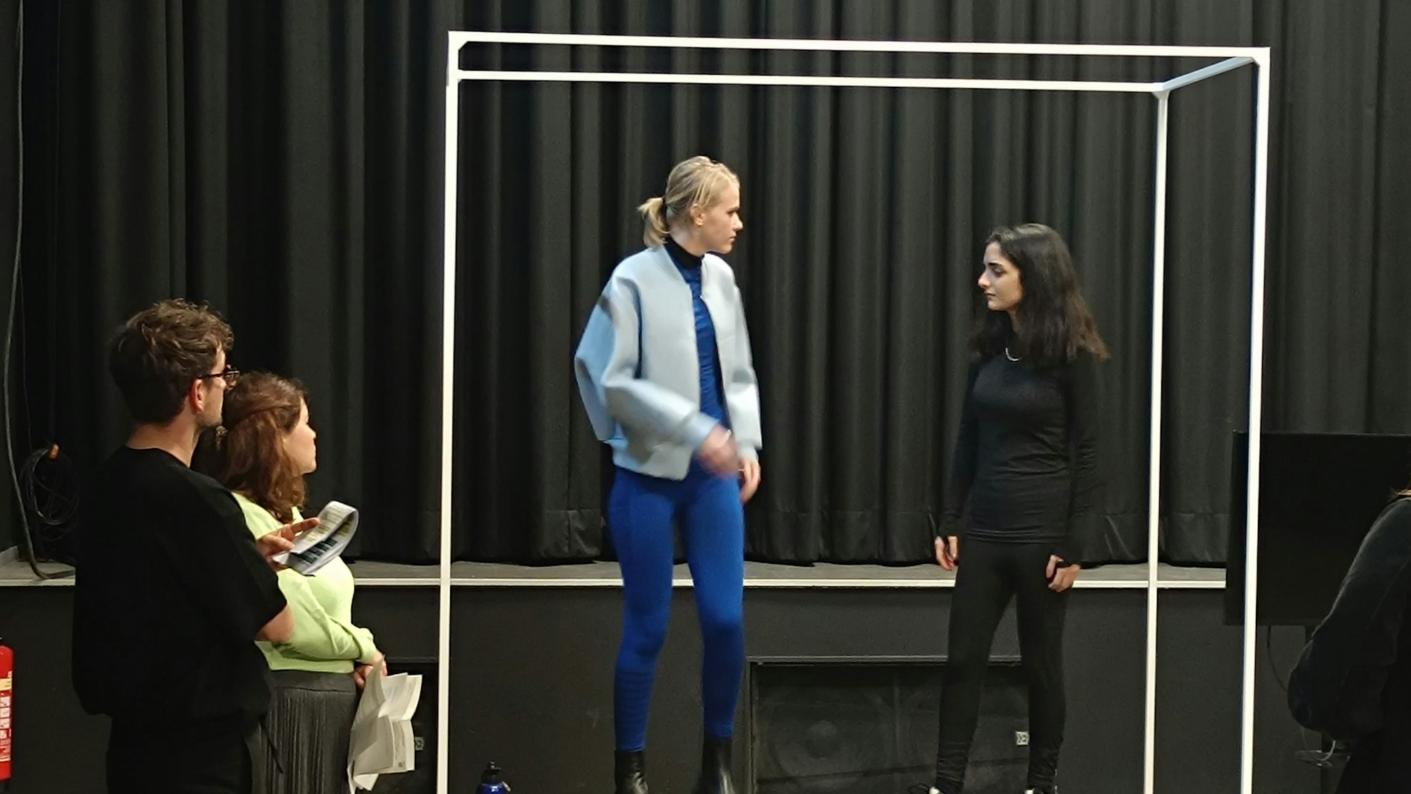 Zu sehen sind zwei der Darsteller bei der Probe auf der Bühne.