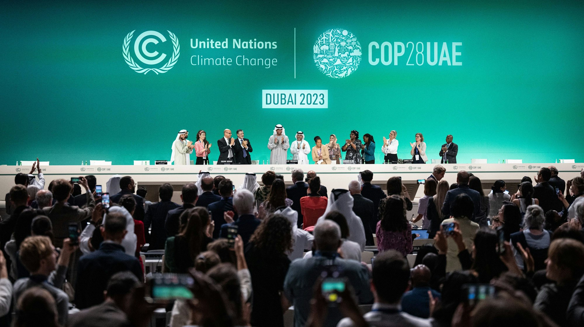 13.12.2023, Vereinigte Arabische Emirate, Dubai: Sultan al-Dschaber, Präsident der COP28, (M) und weitere Teilnehmer auf der Konferenz applaudieren. Am Mittwochmorgen legte die COP-Präsidentschaft einen überarbeiteten Entwurf für den Abschlusstext vor. Dieser wurde zwar nachgeschärft aber enthält kein klares Aus für fossile Brennstoffe. Foto: Hannes P. Albert/dpa +++ dpa-Bildfunk +++