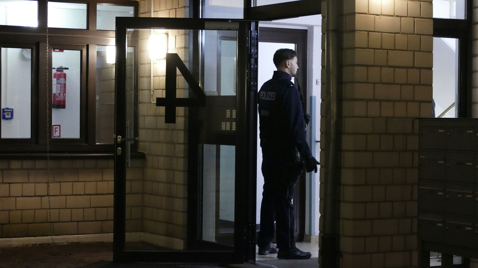 Ein Polizist steht vor einem Hauseingang.