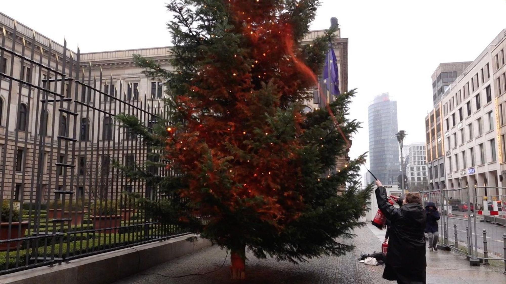 Ein Mitglied der Klimaschutzgruppe ‚Letzte Generation‘ besprüht einen Weihnachtsbaum in Berlin mit Farbe.