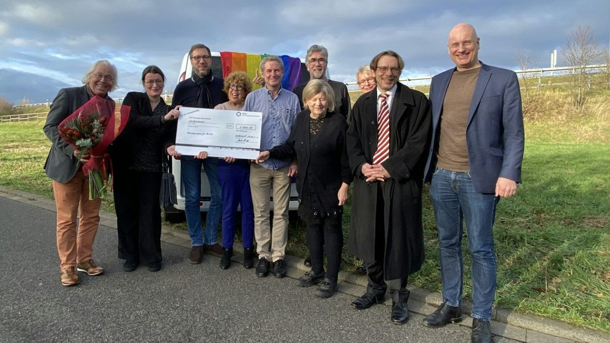 Die Mitglieder der Vereinigung „Gemeinsam für Brühl“ stehen vor einem Wagen mit Regenbogenflagge.