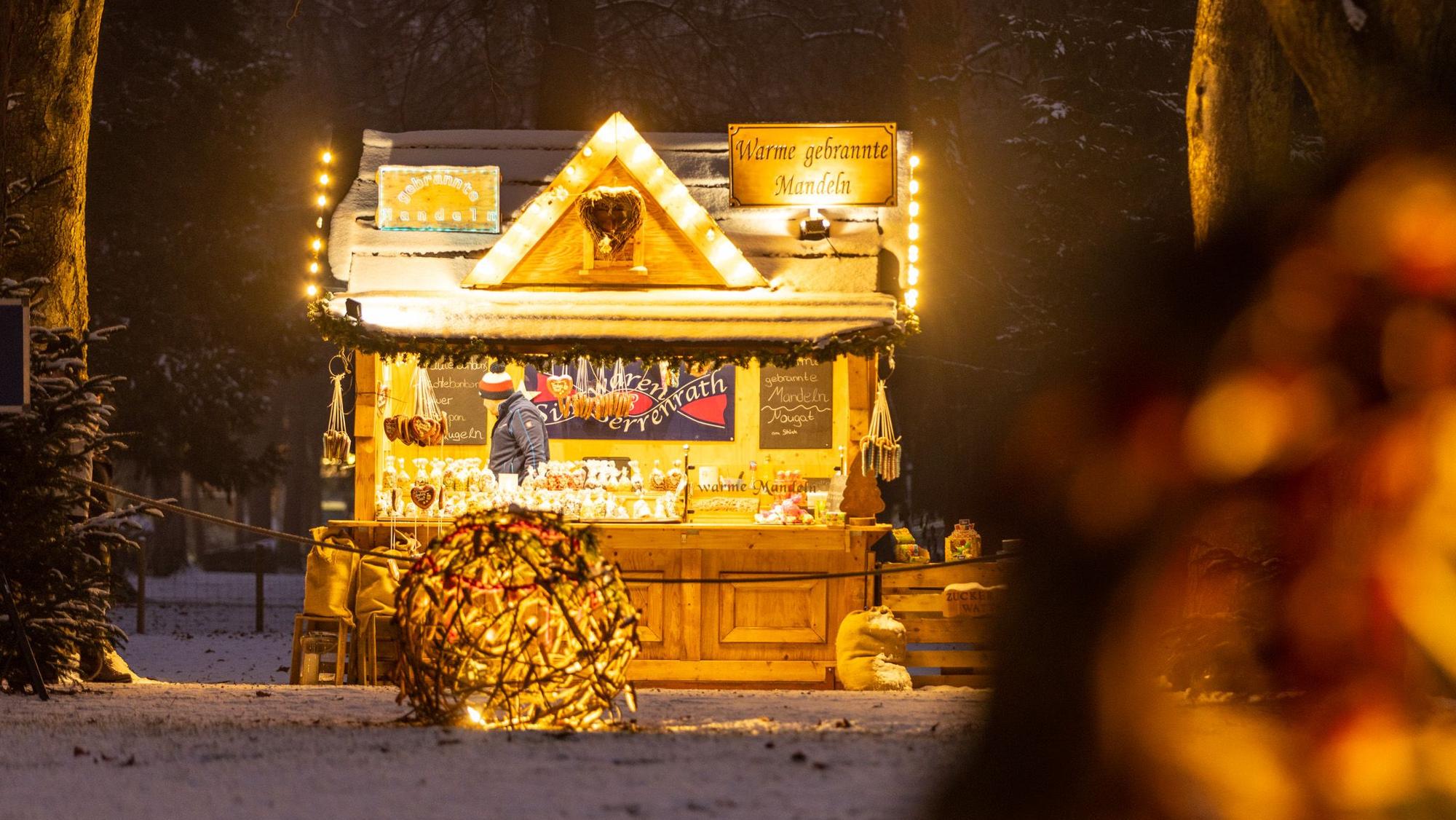 beleuchtete Holzhütte mit Verkaufstresen in einer Winterlandschaft