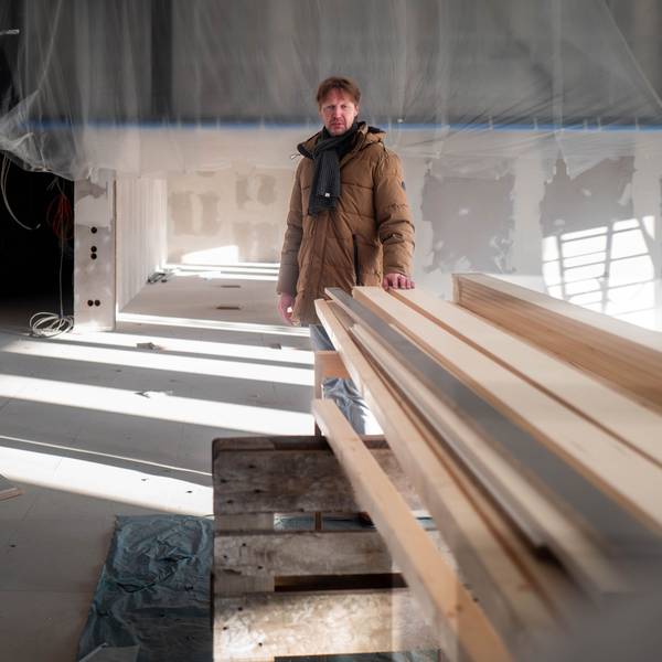 Das Bild zeigt Carsten Opitz hinter einem Stapel Holz, auf den er die linke Hand gelegt hat.