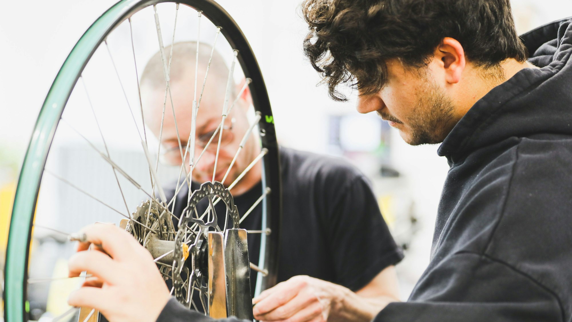 Zwei Männer arbeiten am Hinterreifen eines Fahrrads.