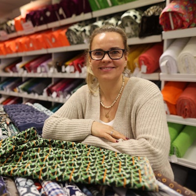 Eine Frau steht inmitten von Stoffballen.