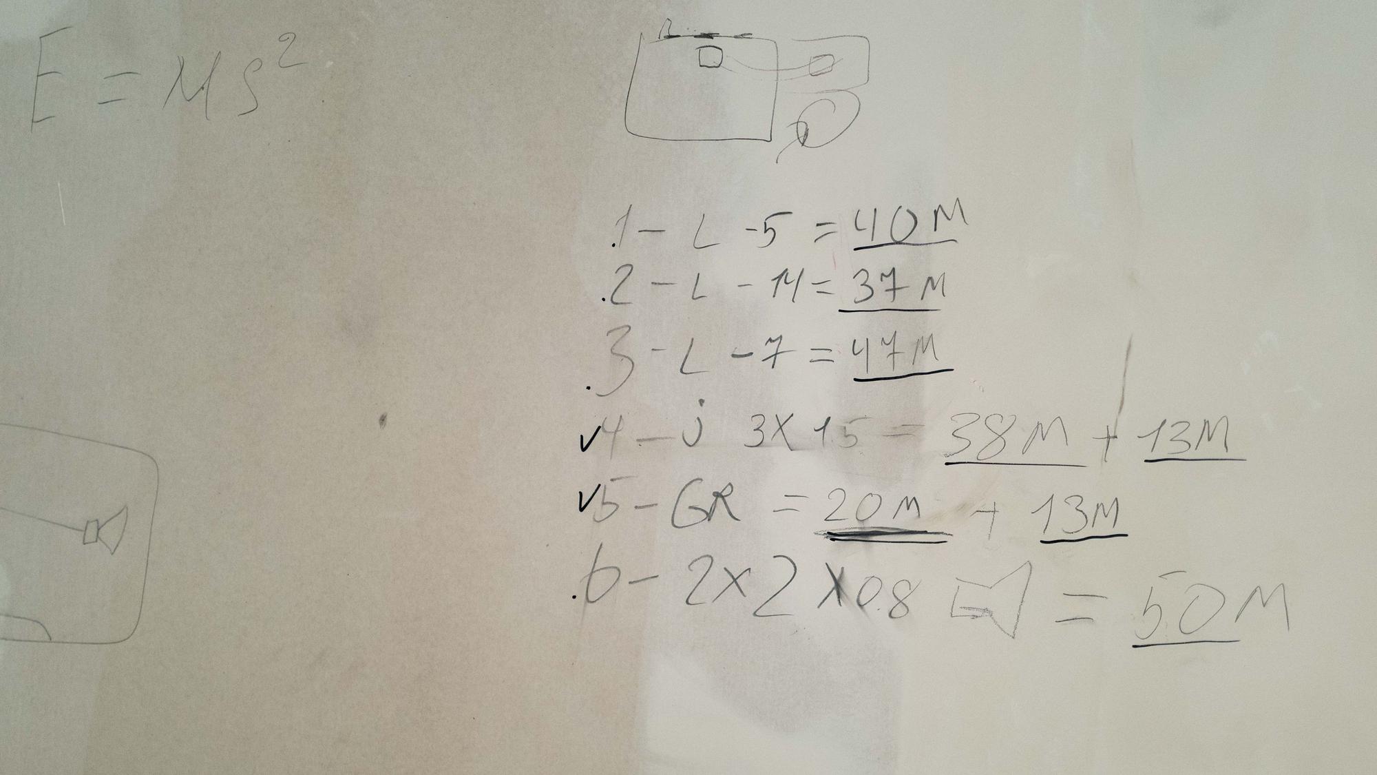 Das Bild zeigt zahlreiche Zahlen und Buchstaben, die mit einem Bleistift an die Wand geschrieben worden sind.