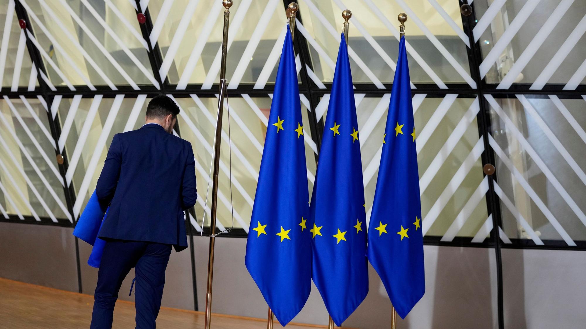 Ein Mann betrachtet drei EU-Flaggen