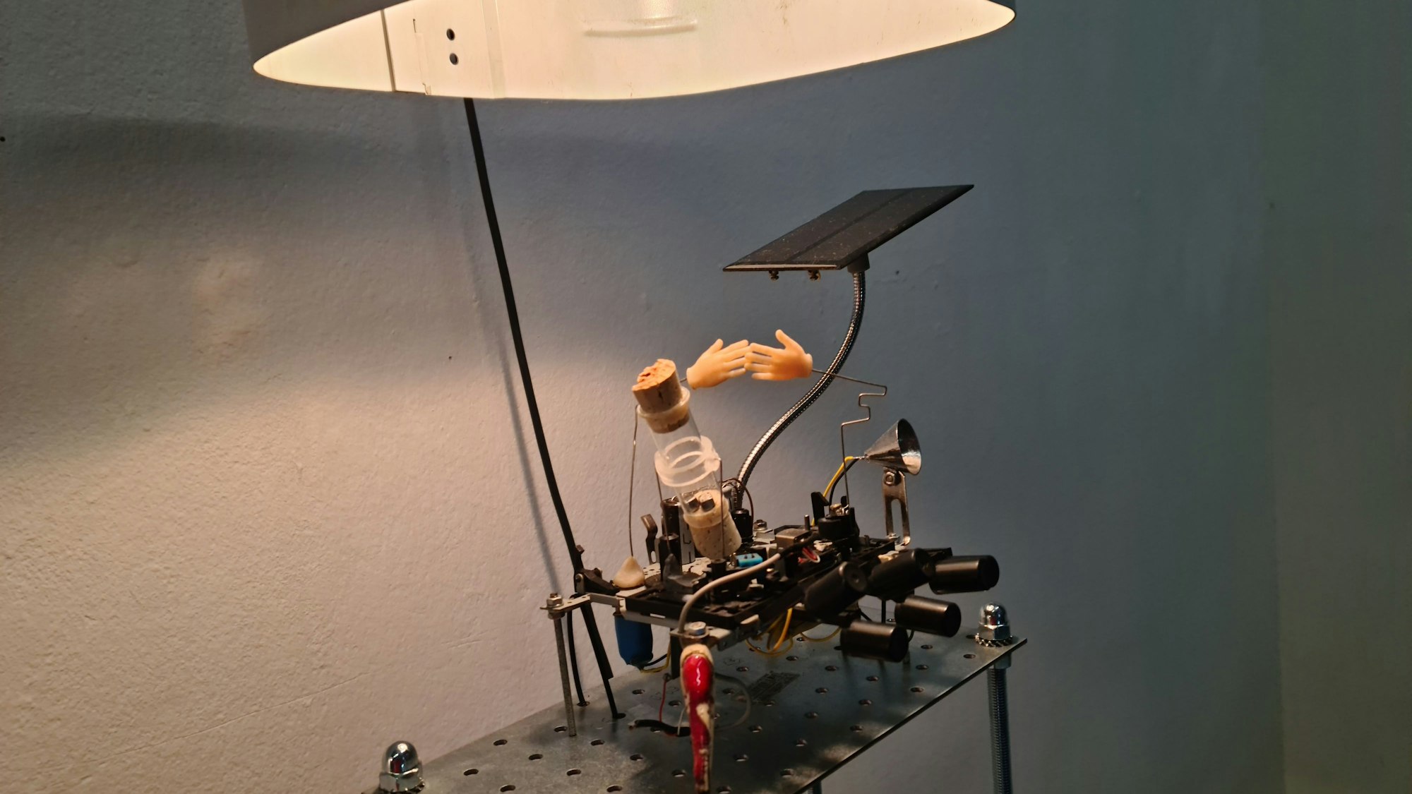 Unter einer Lampe ist ein technisches Konstrukt mit zwei Plastikhänden zu sehen.