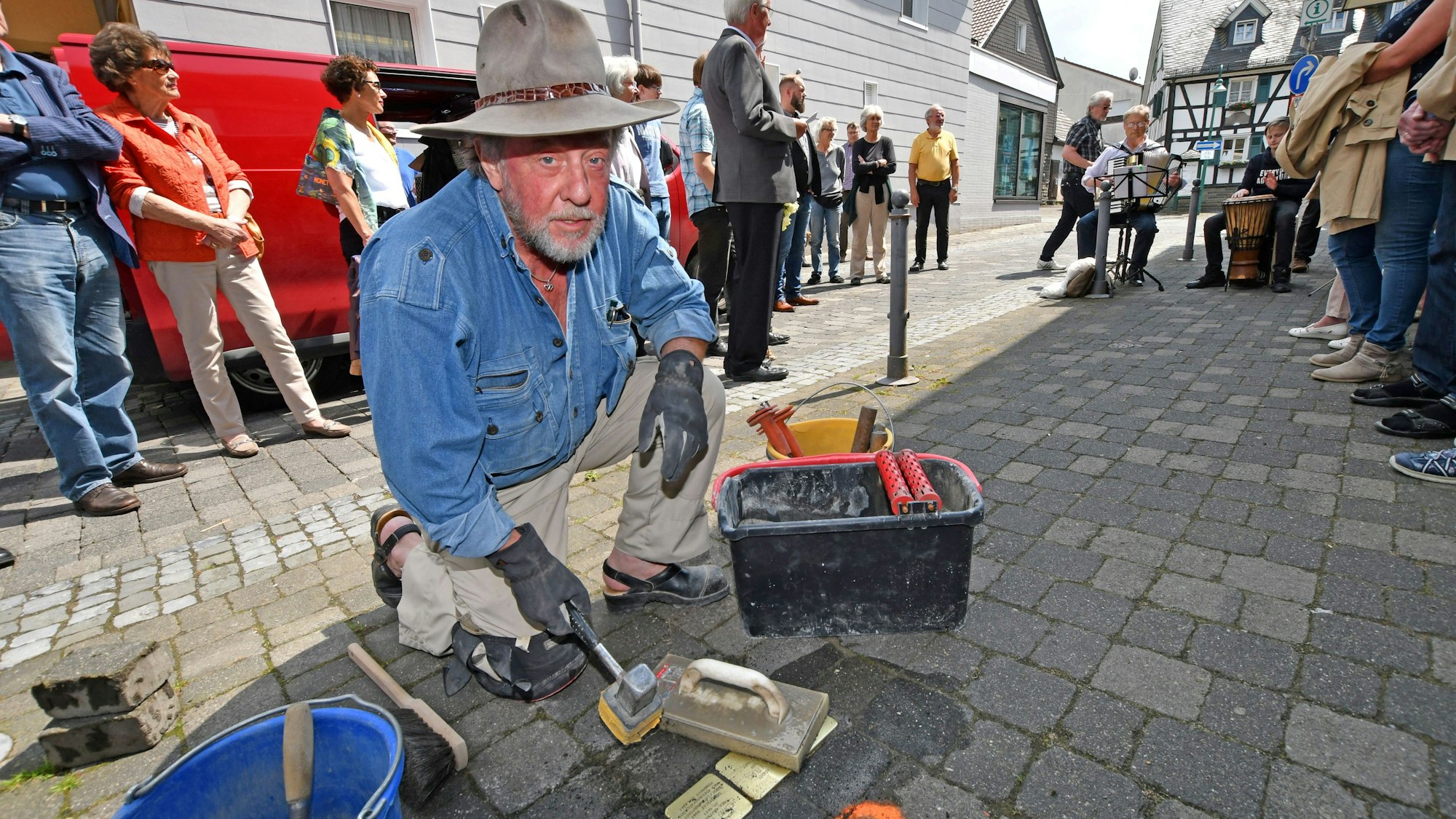 Das Foto zeig den Künstler Günther Demnig beim Verlegen von Stolpersteinen.