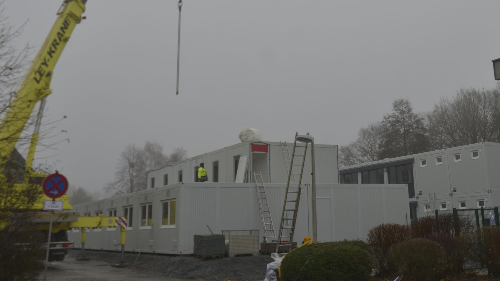 Container für die Unterbringung von Geflüchteten werden auf dem Parkplatz neben der kleinen Turnhalle an der Brionner Straße aufgebaut.