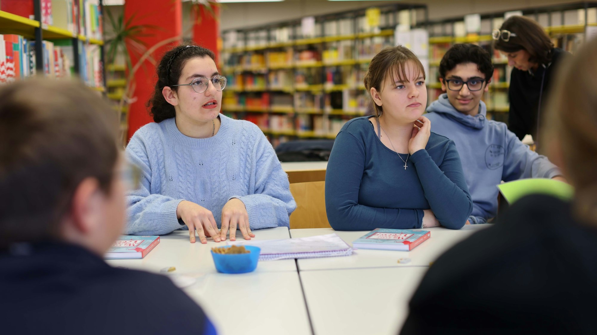 Jugendliche debattieren in einer Bibliothek.