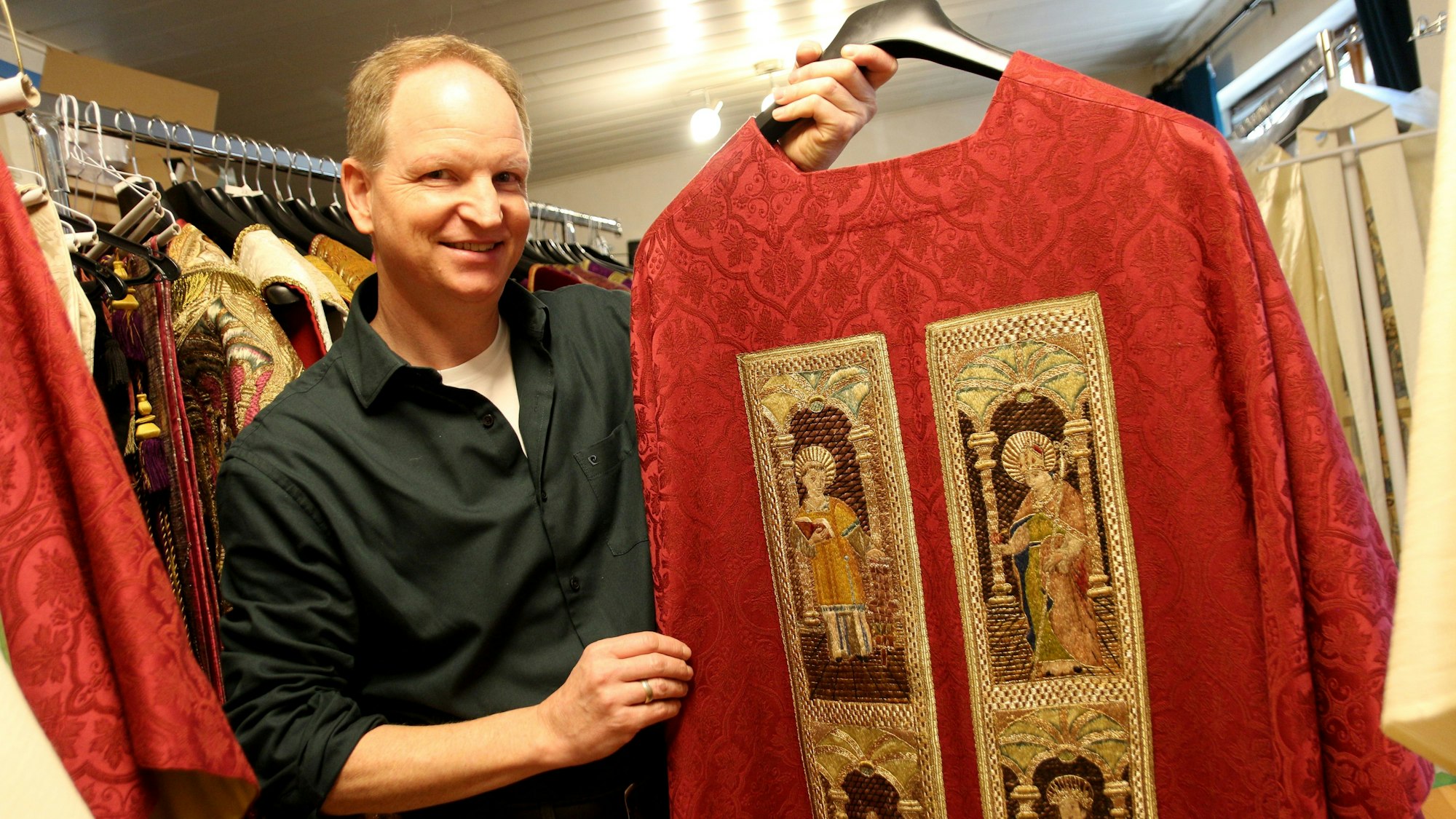 Das Bild zeigt einen Mann, der ein liturgisches Gewand präsentiert.