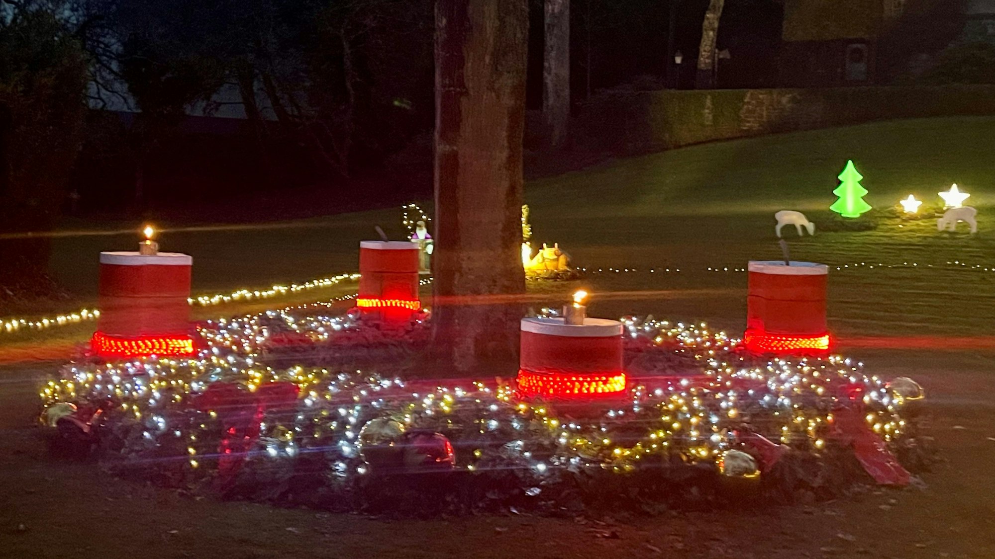 Ein großer, geschmückter Kranz liegt um einen großen Baum herum.