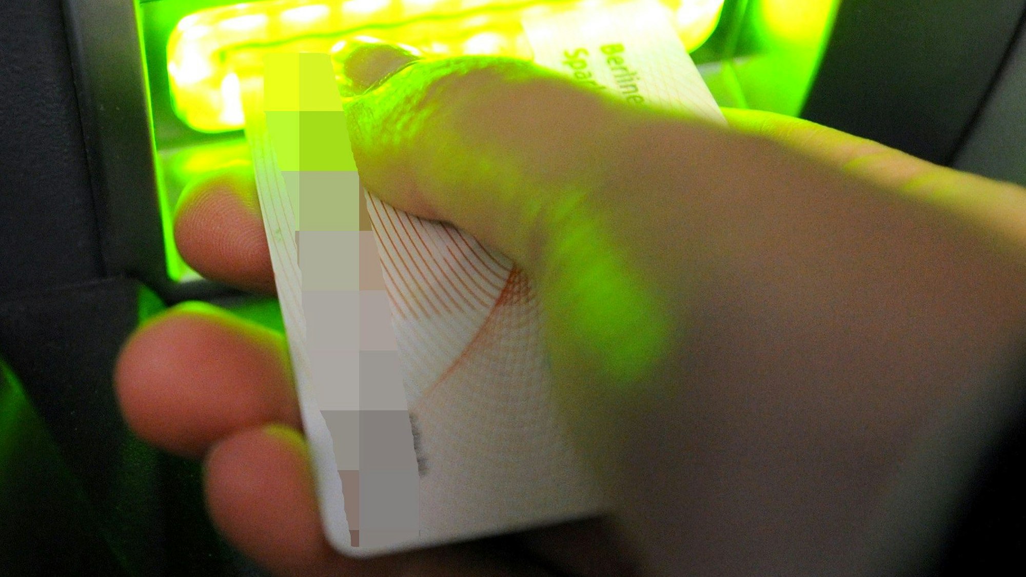 Auf dem Foto ist zu sehen, wie jemand eine Bankkarte in den Schlitz eines Geldautomaten schiebt.