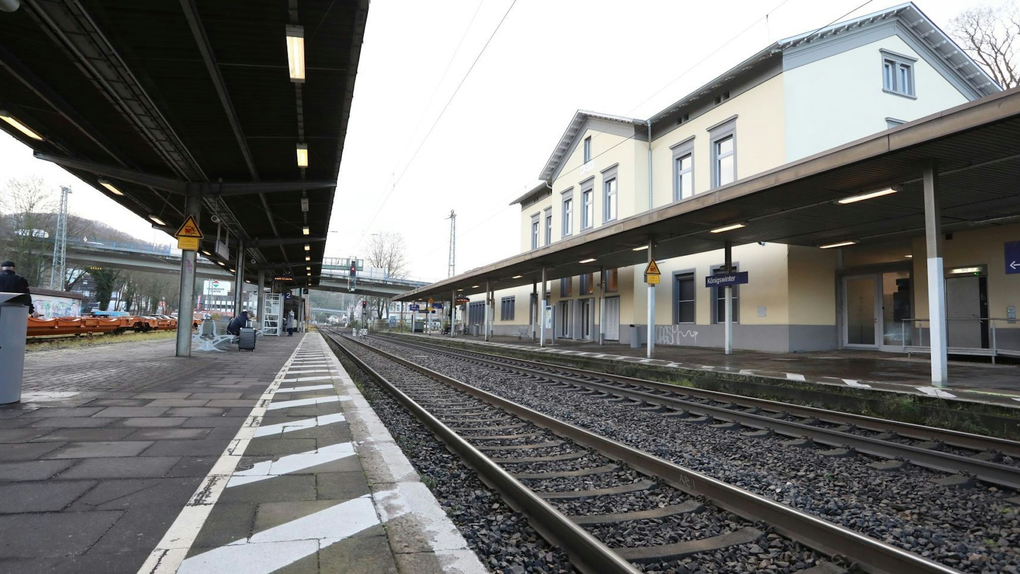 Zwischen einem überdachten Bahnsteig und dem Bahnhofsgebäude verlaufen die Gleise der rechtsrheinischen Bahntrasse.