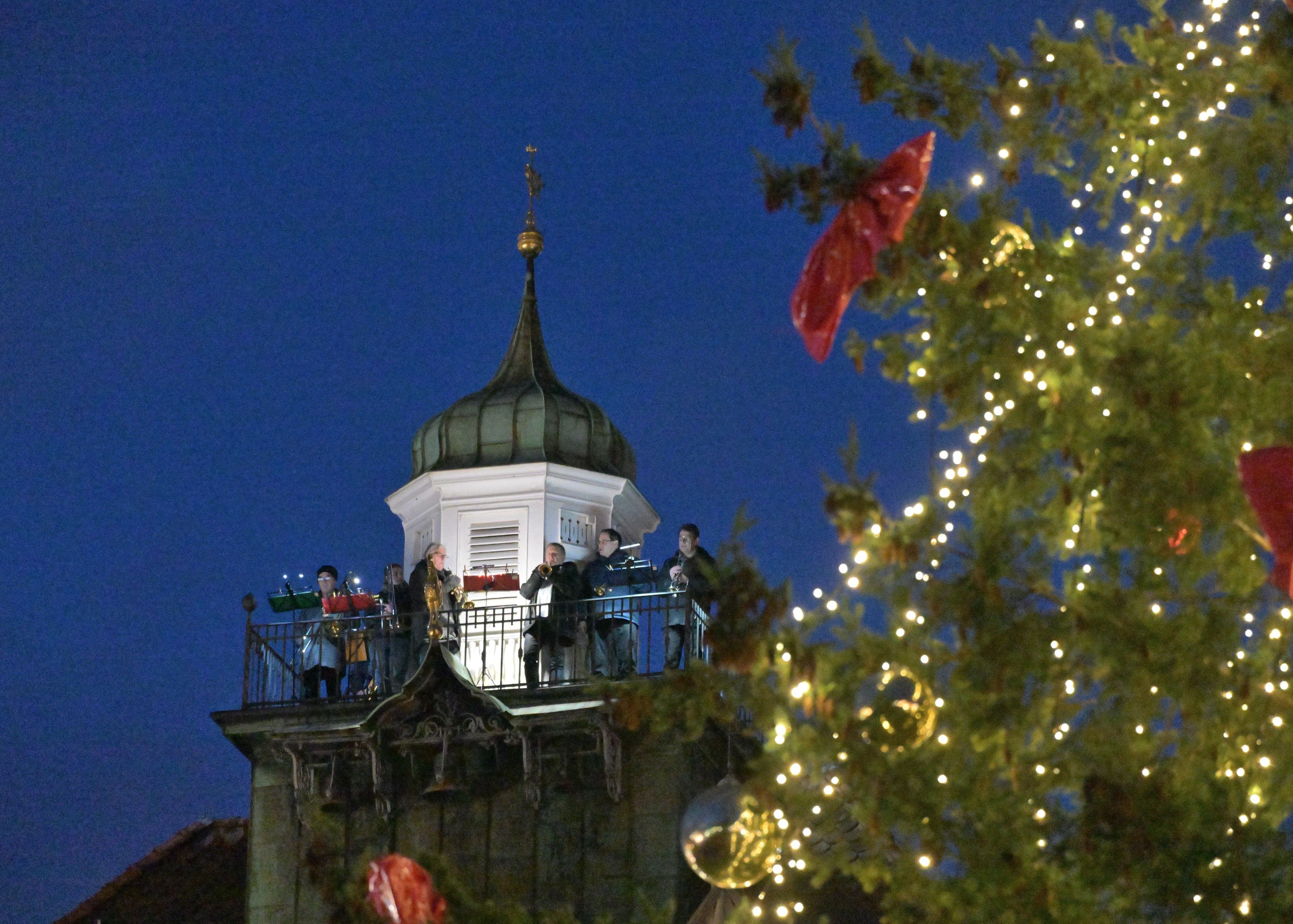 Musiker spielen auf dem Turm des Bergisch Gladbacher Rathauses, im Vordergrund ist ein Weihnachtsbaum zu sehen.