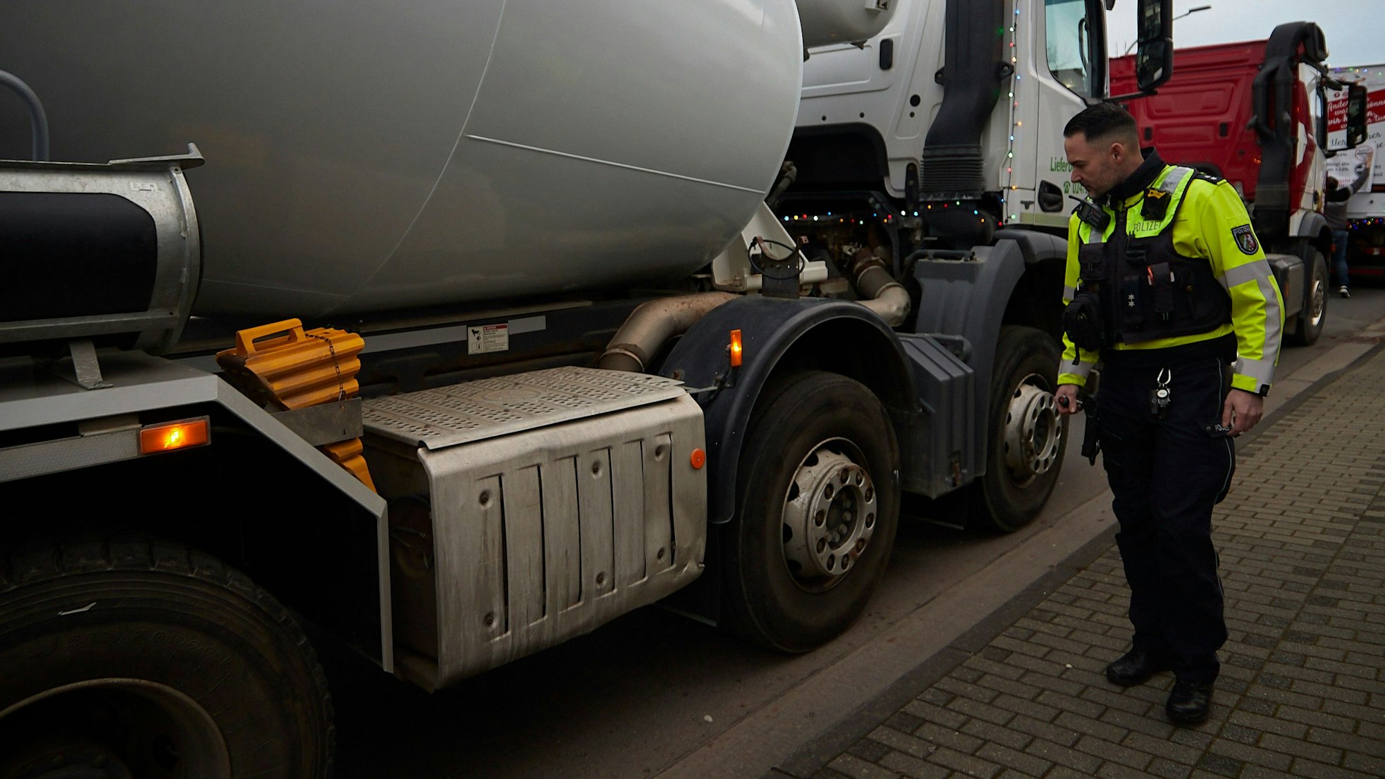 Das Bild zeigt den Polizisten, wie er einen kritischen Blick auf einen Lkw wirft.
