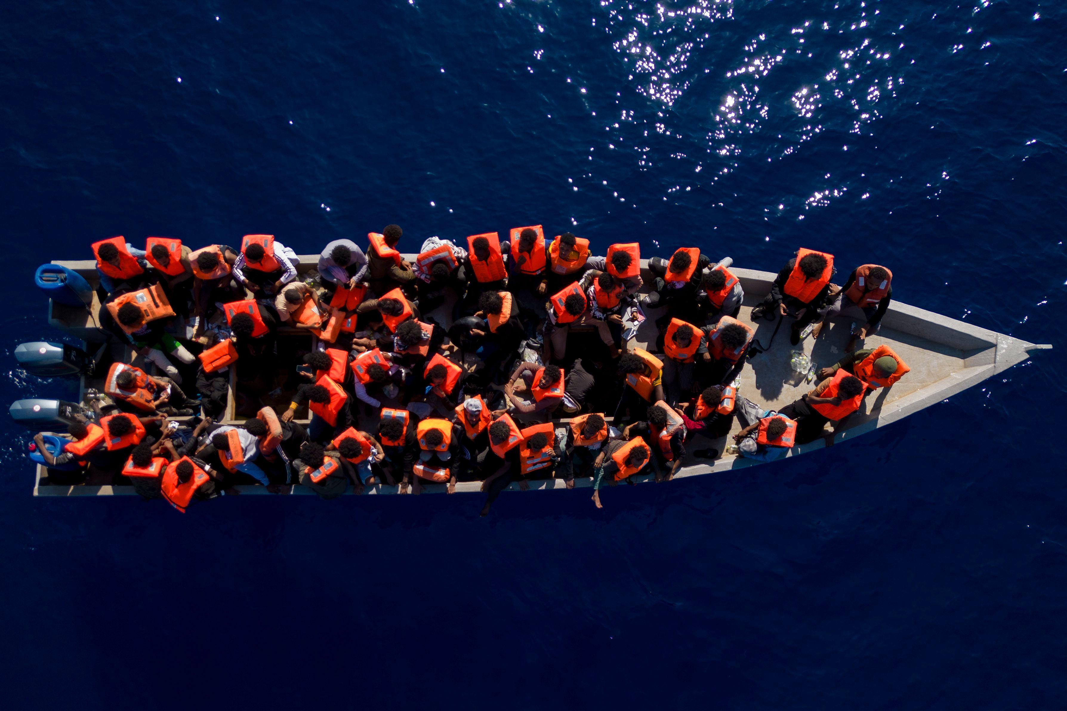 ARCHIV - 17.06.2023, ---: Migranten aus Eritrea, Libyen und dem Sudan sitzen in einem Holzboot, bevor sie von Helfern der spanischen Nichtregierungsorganisation Open Arms im Mittelmeer, etwa 30 Meilen nördlich von Libyen, unterstützt werden. Foto: Joan Mateu Parra/AP/dpa +++ dpa-Bildfunk +++