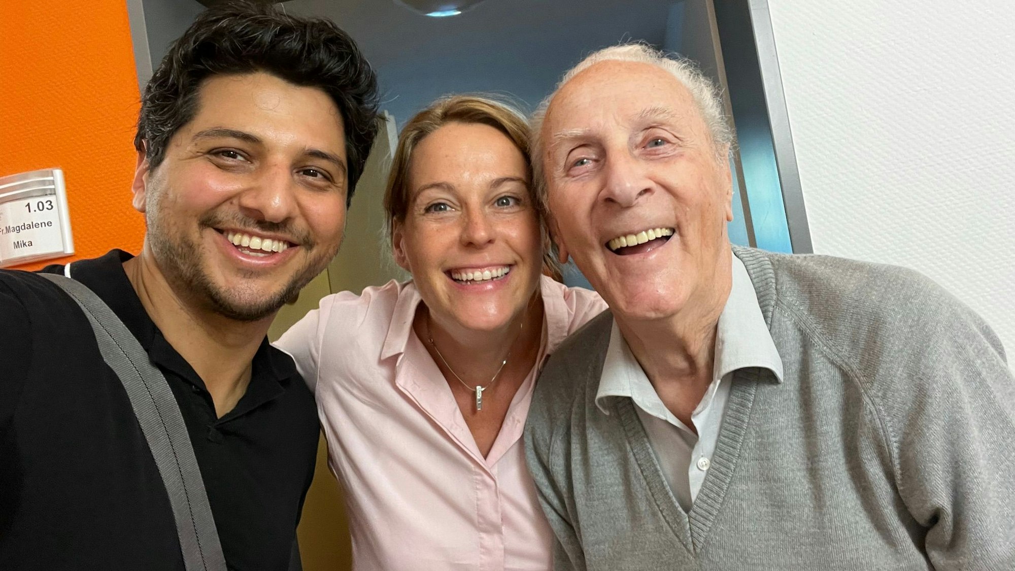 Zwei Filmemacher lächeln gemeinsam mit ihrem 93-jährigen Interviewpartner in die Kamera.