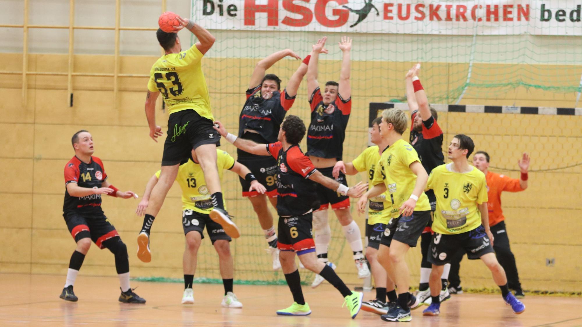 Zwei Palmersheimer Spieler springen hoch, um einen Torwurf abzuwehren.Rund um sie herum stehen Mitspieler und Gegner.
