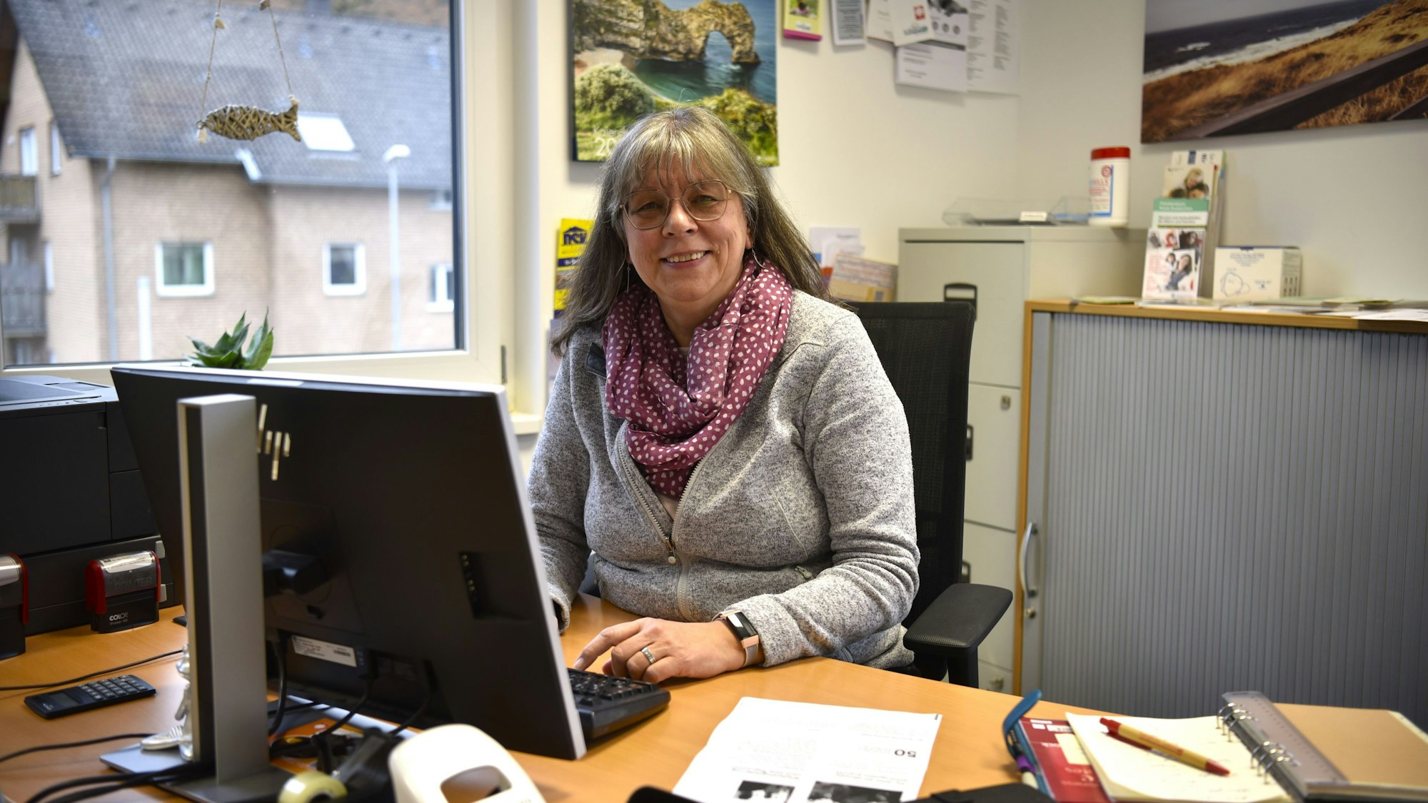 Das Bild zeigt Marion Engels an ihrem Schreibtisch sitzend.