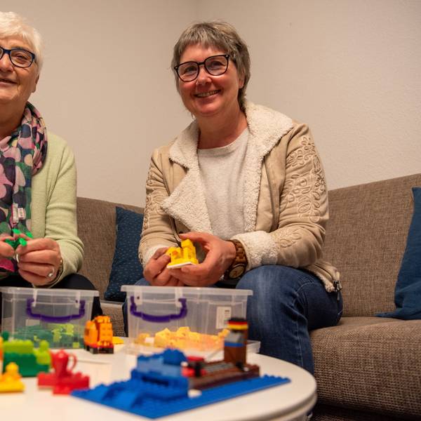 Das Bild zeigt Anita Sauer (l.) und Vera Schröder auf einem Sofa sitzend. Vor ihnen steht auf einem Tisch Lego-Spielzeug.