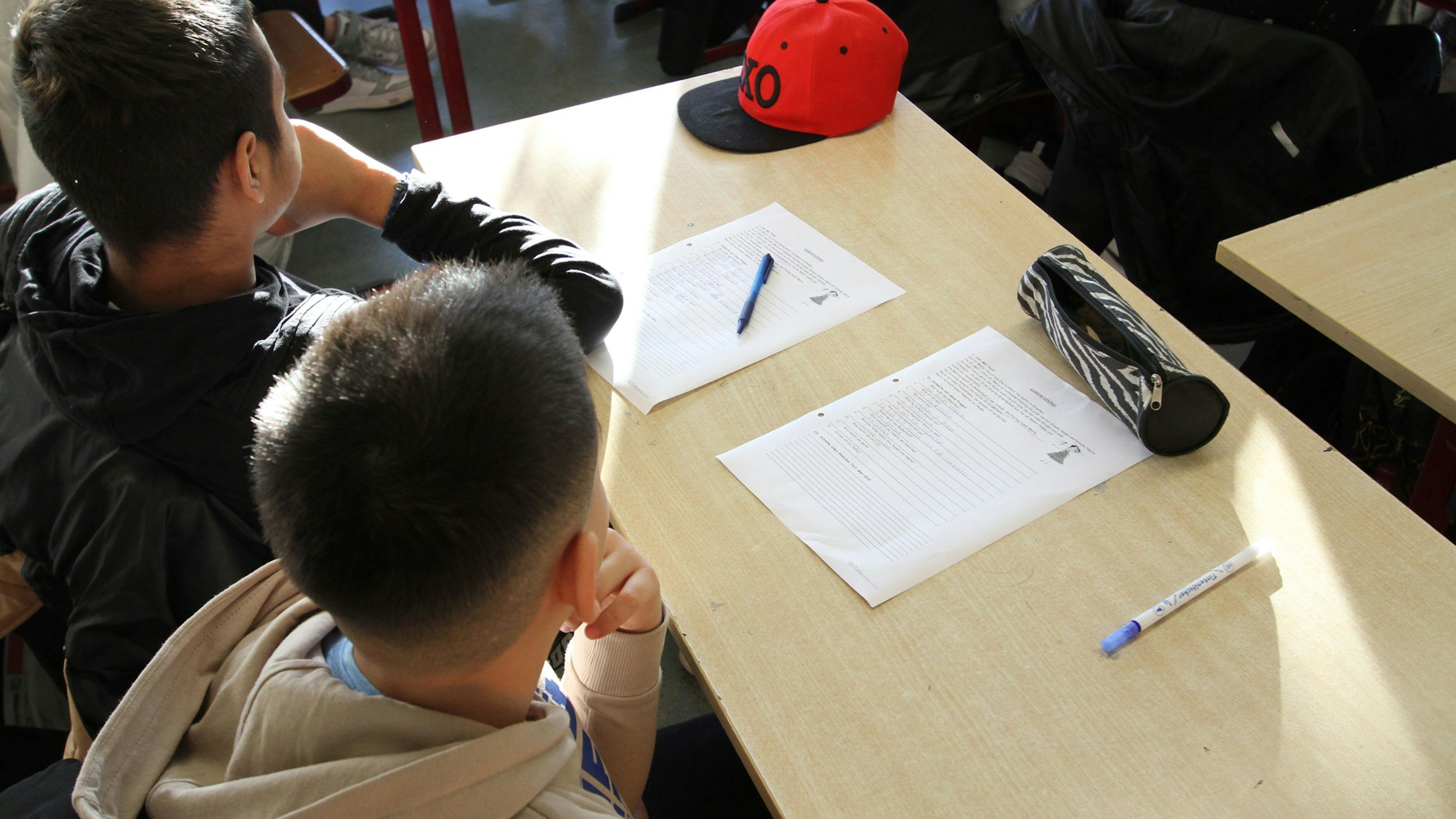 Zwei Schüler mit Arbeitsbögen an einem Tisch