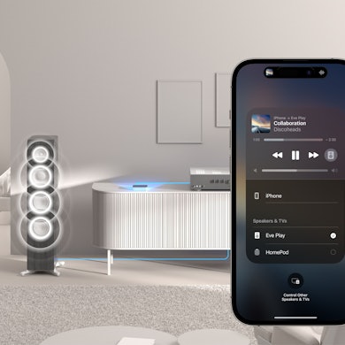 Ein Wohnzimmer mit Stereoanlage, im Vordergrund ein Smartphone.