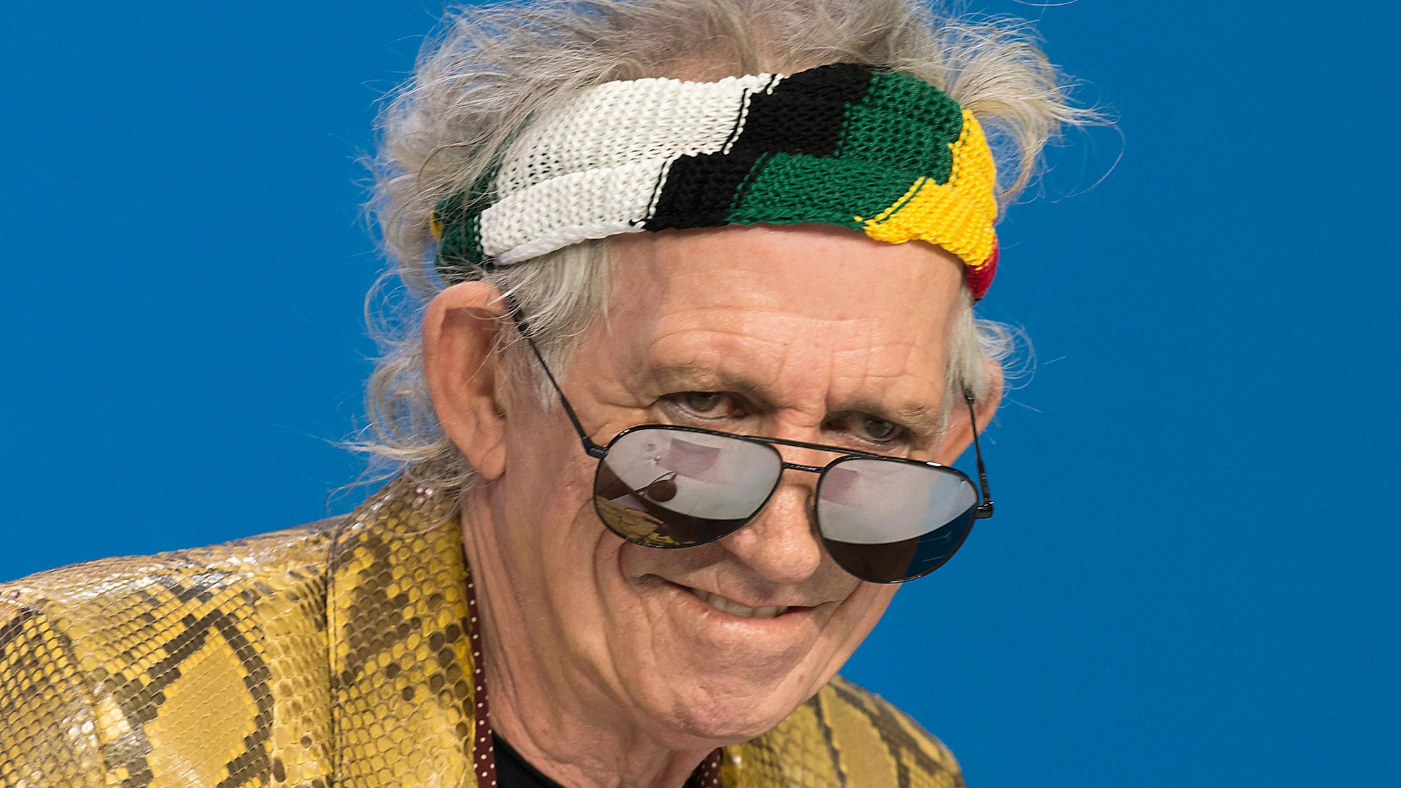 Keith Richards schaut über seine Sonnenbrille und trägt ein buntes Stirnband.